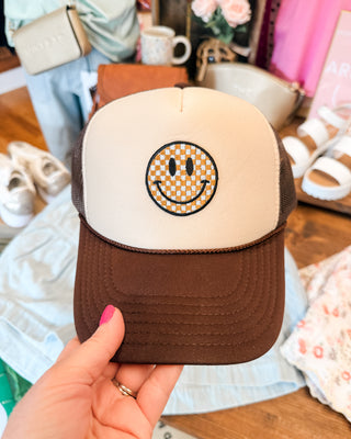 a brown foam trucker hat with checkered smiley face