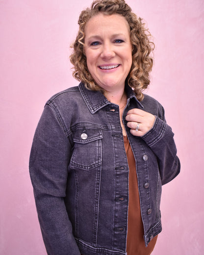 Woman wearing a denim jacket against a pink background