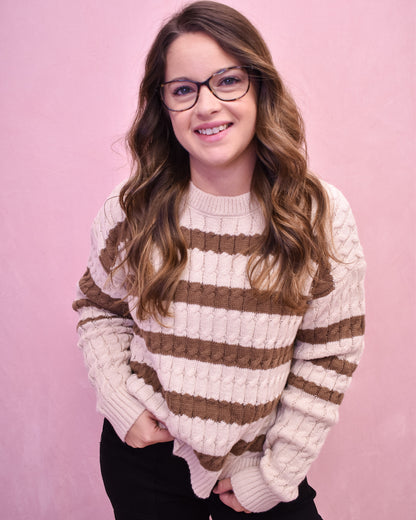 Woman wearing a striped sweater against a pink background