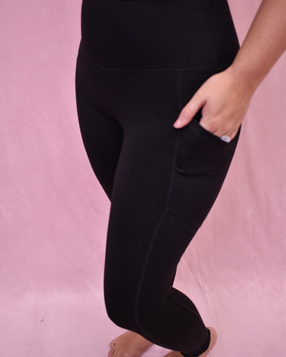 Person wearing black leggings on a pink background