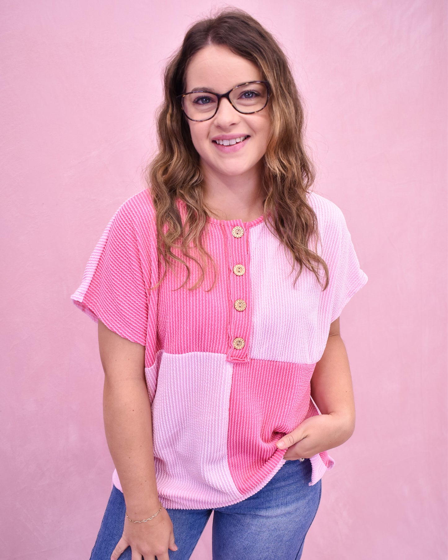 Woman wearing a pink and white top with a pink background