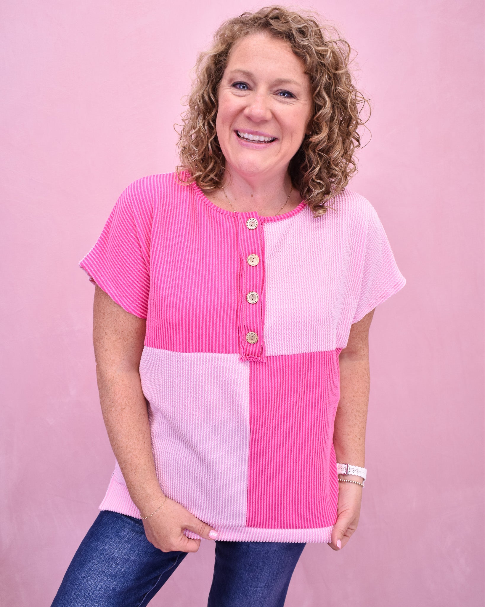 Woman wearing a pink and white color-blocked top against a pink background