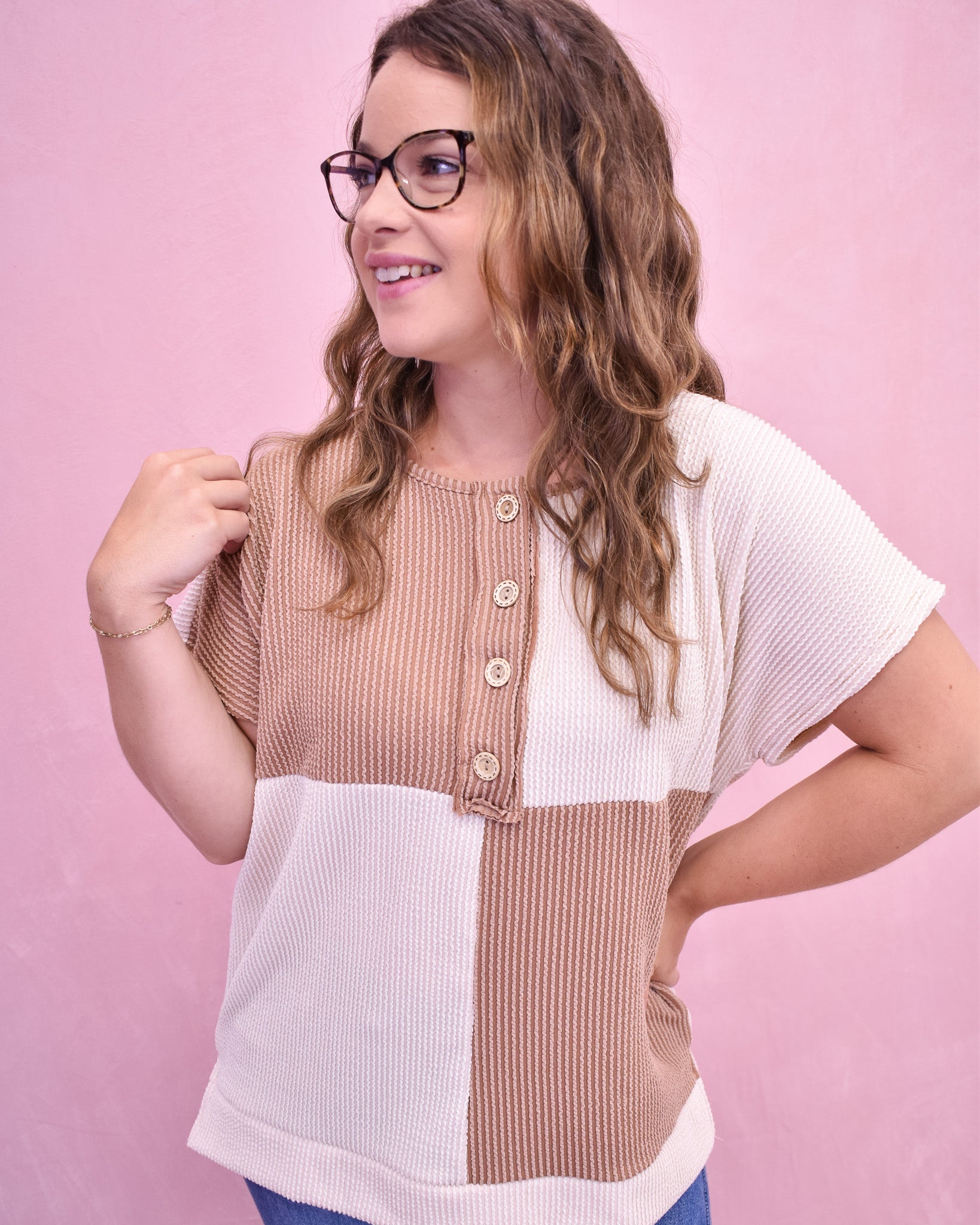 Woman wearing a two-tone top with a pink background