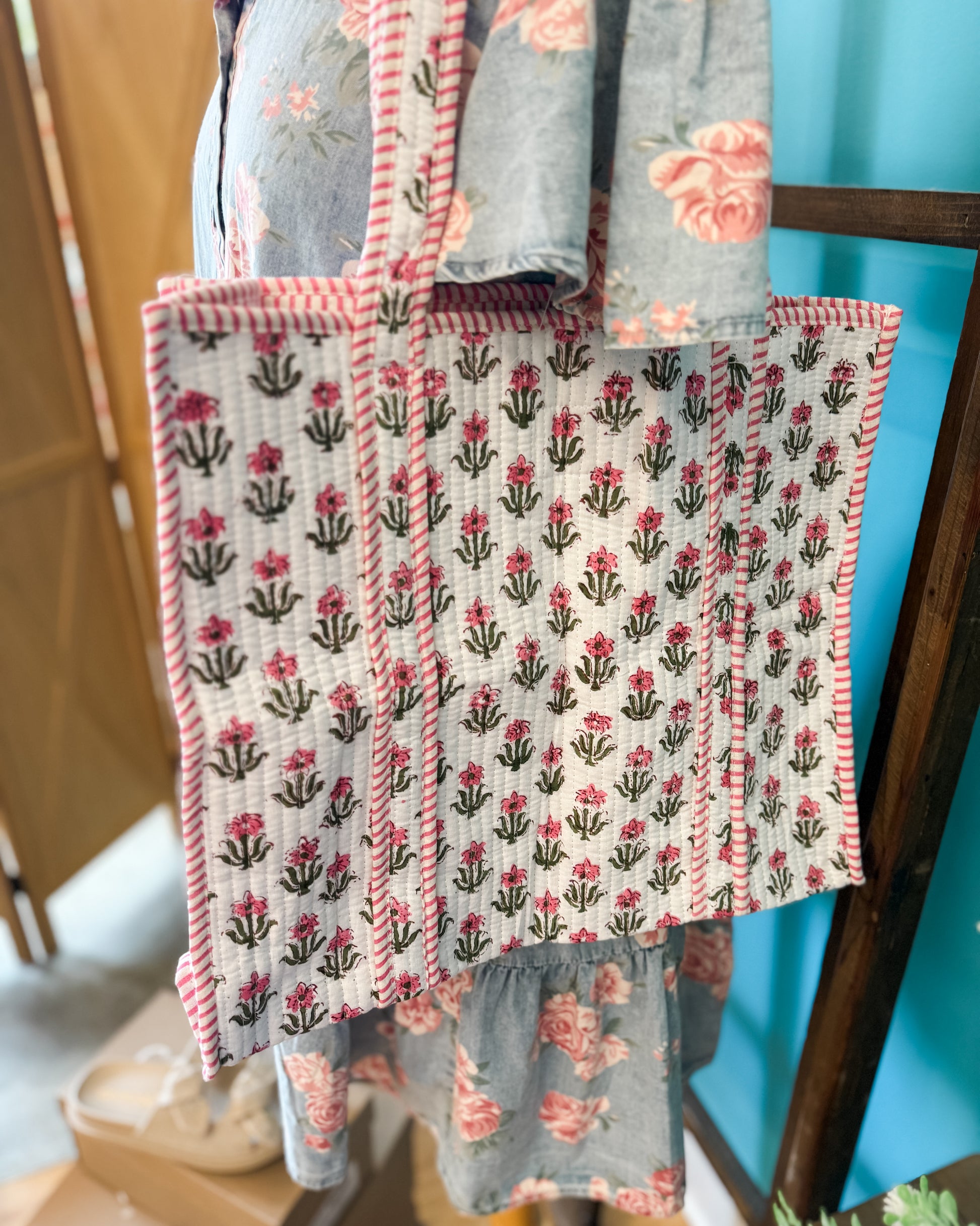 Floral patterned fabric hanging on a wooden chair against a blue wall.