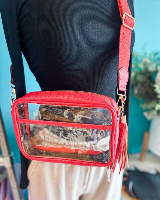 A clear crossbody stadium style bag with red trim