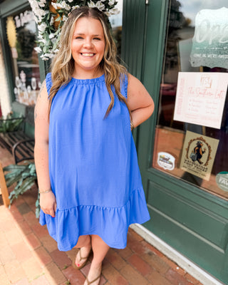 an indigo blue drop hem dress with ruched sleeves and neckline.