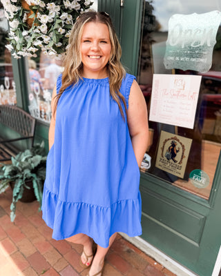 an indigo blue drop hem dress with ruched sleeves and neckline.