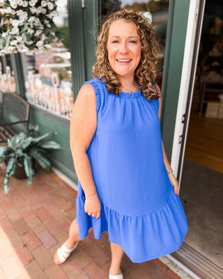 an indigo blue drop hem dress with ruched sleeves and neckline.