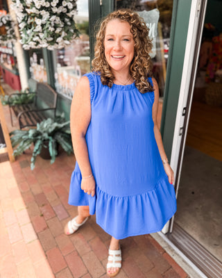 an indigo blue drop hem dress with ruched sleeves and neckline.