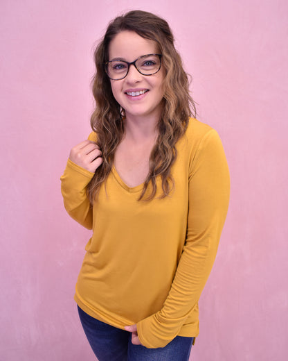 Woman wearing a yellow long-sleeve shirt against a pink background