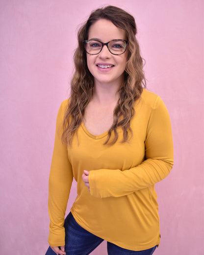 Woman wearing a yellow long-sleeve shirt against a pink background