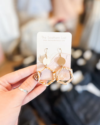 A hexagon dangle style earring with a gold disk drop in a mustard and cream print