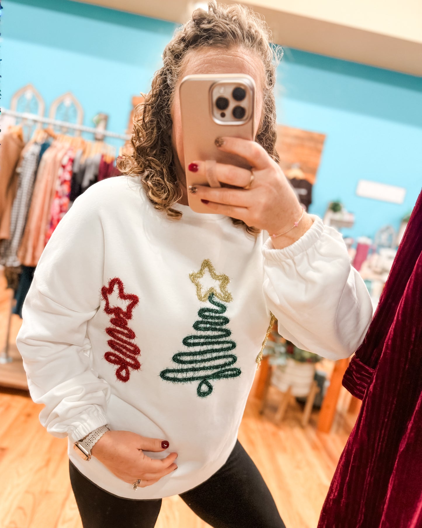 Person wearing a white sweatshirt with Christmas-themed designs in a store setting.