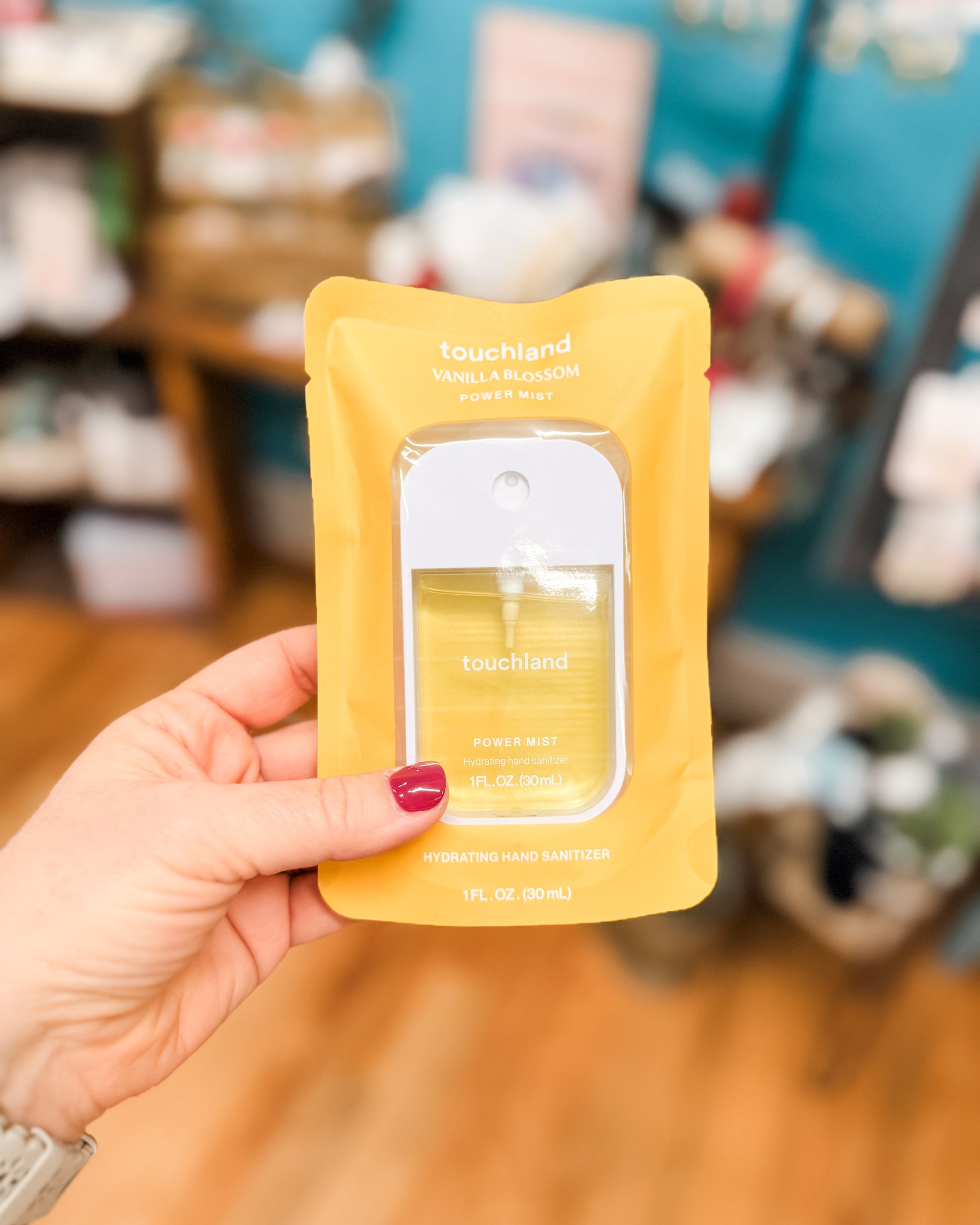 Hand holding a yellow skincare sample packet with a blurred indoor background