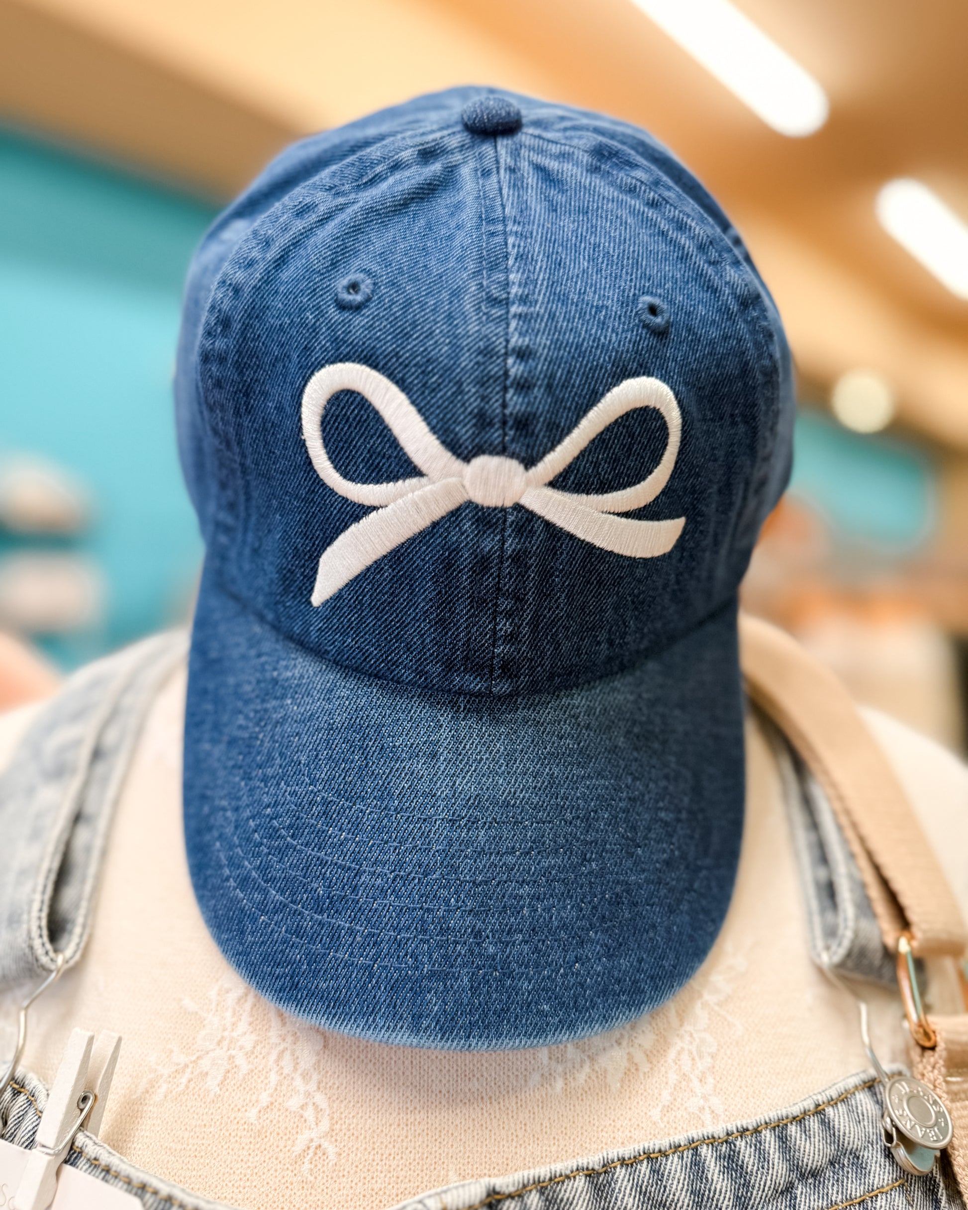 Blue denim cap with a white bow design on a blurred background