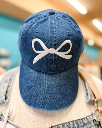 Blue denim cap with a white bow design on a blurred background