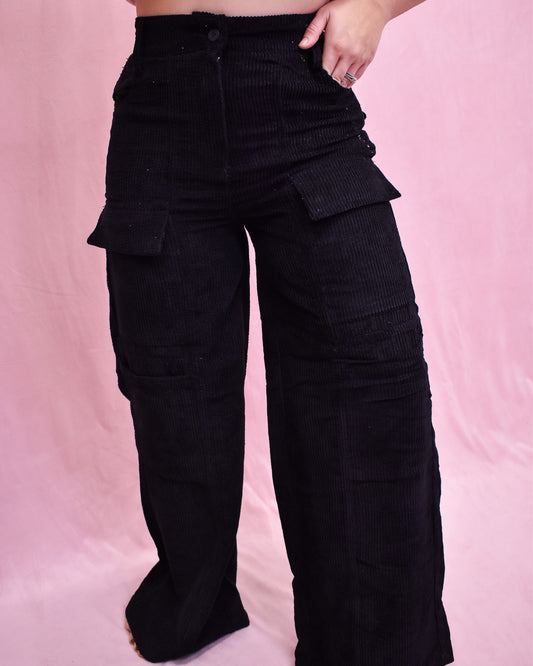 Black cargo pants worn by a person on a pink background