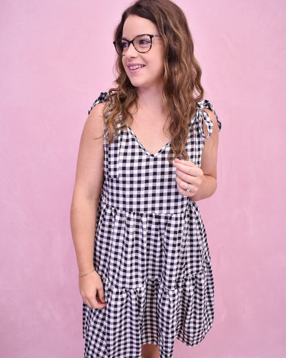 Woman wearing a black and white checkered dress against a pink background