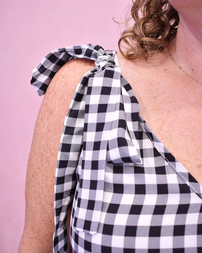 Black and white checkered top worn by a person on a pink background