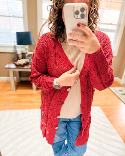 Person wearing a red cable knit cardigan taking a mirror selfie.