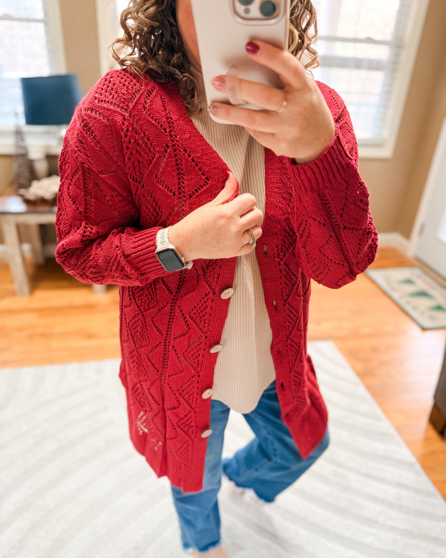 Person wearing a red knitted cardigan taking a mirror selfie.