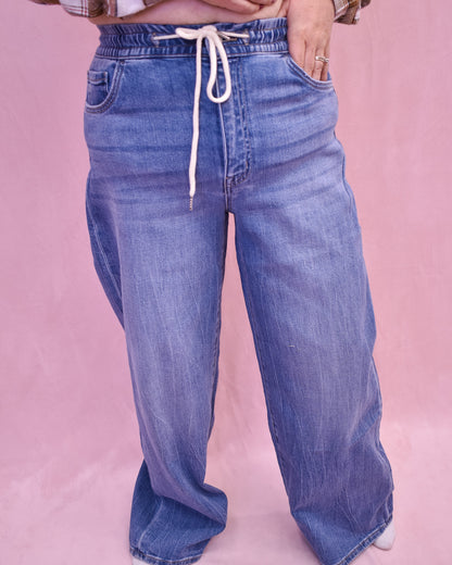 Blue jeans with a drawstring on a pink background