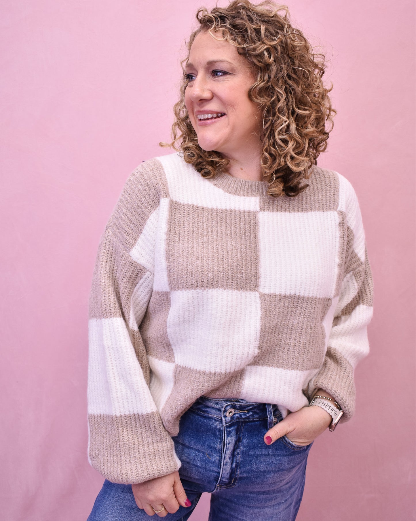 Woman wearing a checkered sweater against a pink background