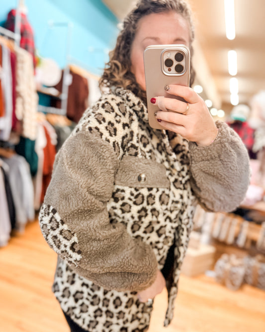 Person wearing a leopard print coat with gray trim in a store setting