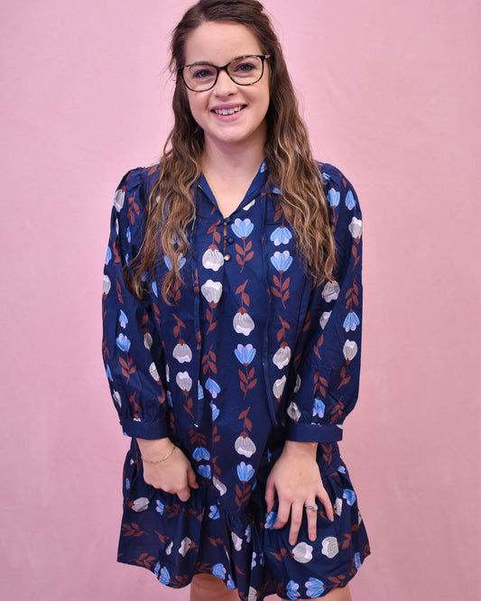 Woman wearing a blue floral dress against a pink background